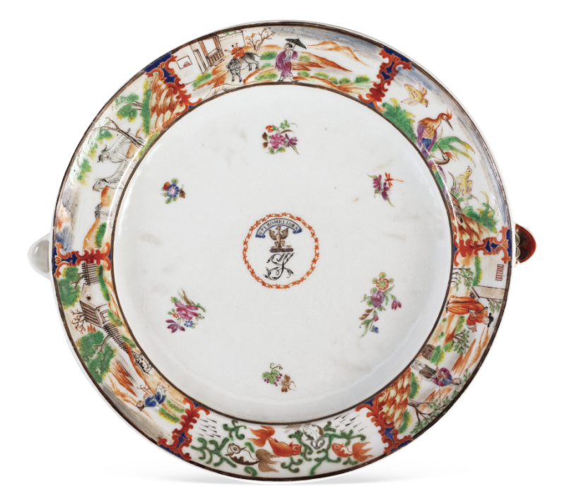 圖為清嘉慶廣彩描金花卉人物紋章溫盤，盤沿兩側(cè)對稱置半圓形注水口。外邊飾為鄉(xiāng)村風(fēng)景紋，盤心繪紋章，四周繪六組折枝花卉圍繞。溫盤又稱暖盤，使用時將熱水由孔注入，使盛入淺盤的食物保溫，達到防冷溫?zé)岬男Ч?。（來源：廣州十三行博物館）